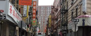 Calles de Chinatown en Nueva York con letreros en chino, tiendas y ambiente urbano animado.
